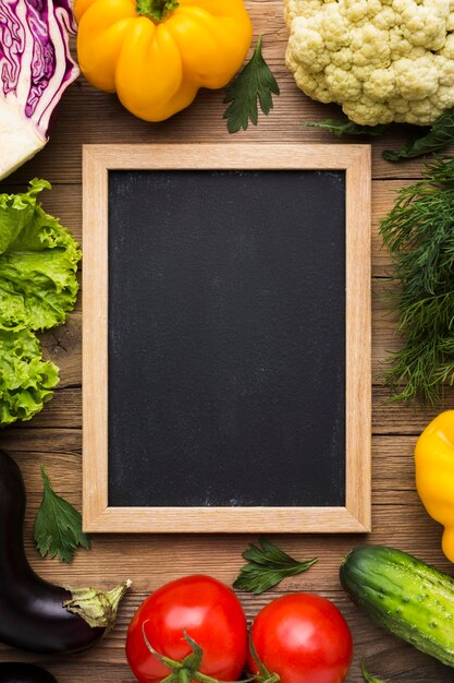 Vue de dessus fond coloré avec légumes et tableau noir