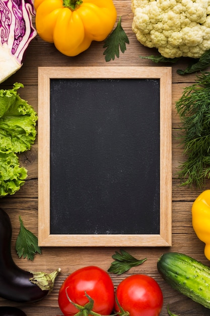 Vue de dessus fond coloré avec légumes et tableau noir