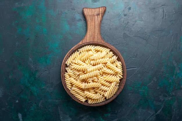 Vue de dessus en forme de pâtes italiennes délicieuses à la recherche de petites pâtes sur le bureau bleu foncé