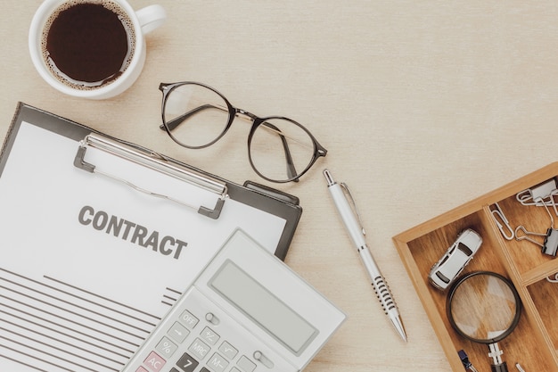 Photo gratuite vue de dessus formulaire de contrat d'affaires avec des lunettes de café stylo calculatrice de voiture avec une loupe sur fond en bois.