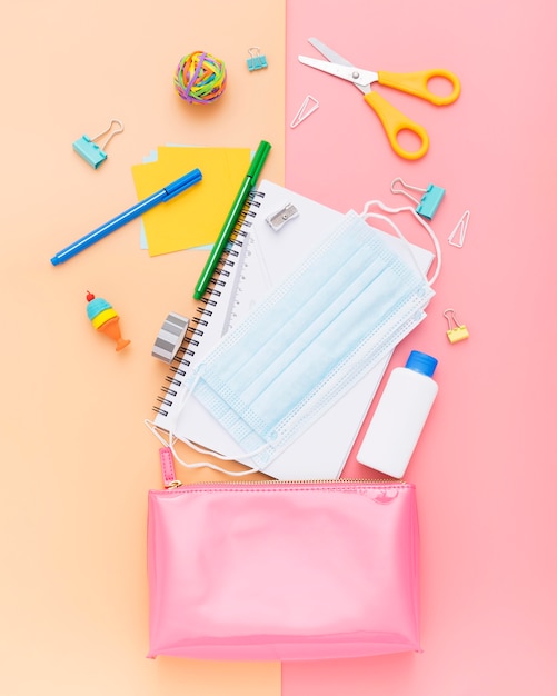 Vue de dessus des fournitures scolaires avec carnet et masque facial