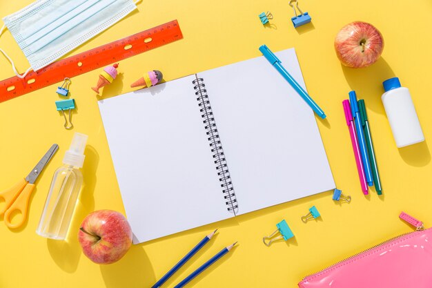 Vue de dessus des fournitures scolaires avec carnet et pommes