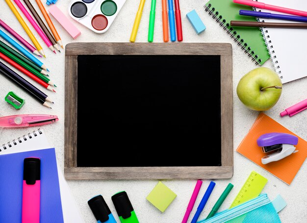 Vue de dessus des fournitures scolaires avec des crayons colorés et un tableau noir