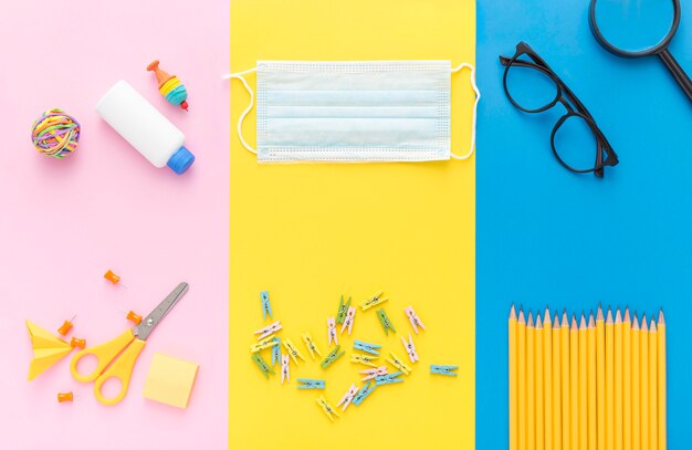 Vue de dessus des fournitures scolaires avec masque médical et crayons