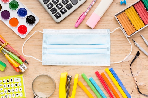 Vue de dessus des fournitures scolaires avec masque médical et masque coloré