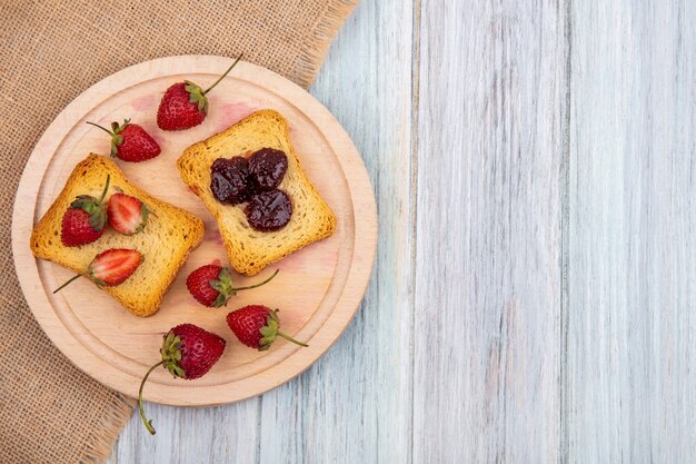 Vue de dessus de fraise sur une planche de cuisine en bois sur un tissu de sac sur un fond en bois gris avec espace copie