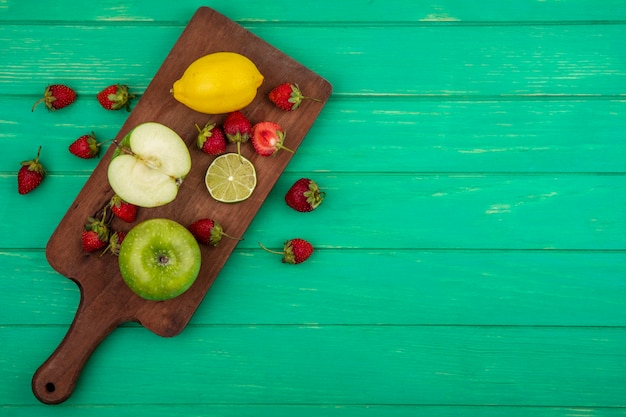 Vue de dessus de fraise avec pomme verte sur une planche de cuisine en bois sur fond vert avec espace copie