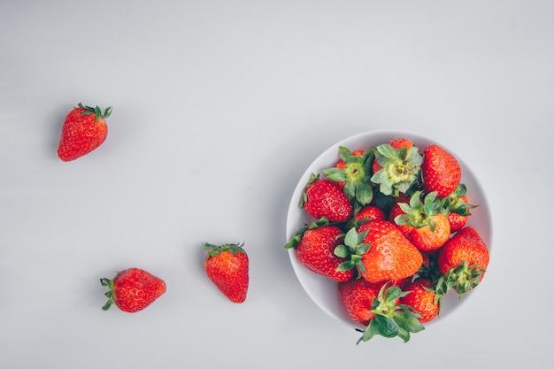 Vue de dessus des fraises dans un bol sur fond blanc. horizontal