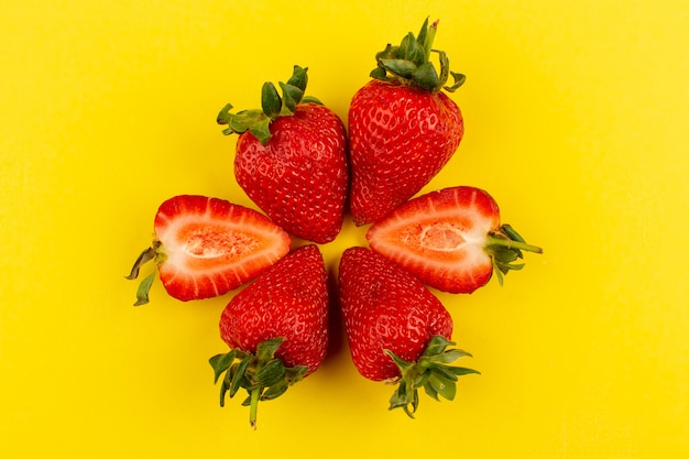 Vue de dessus des fraises fraîches moelleuses ensemble juteux tranché sur le sol jaune