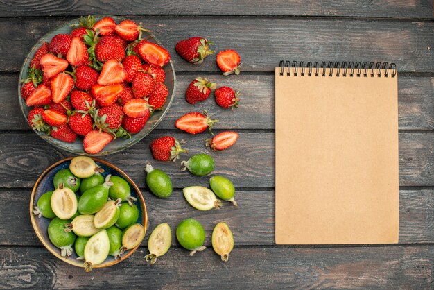 Vue de dessus des fraises rouges avec des feijoas fraîches sur un bureau rustique en bois foncé