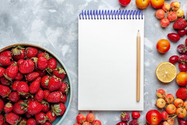 Vue de dessus fraises rouges fraîches avec d'autres fruits sur le bureau léger fruit berry vitamine fraîche