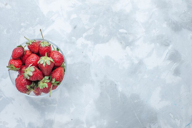 Vue de dessus des fraises rouges fraîches baies d'été moelleuses à l'intérieur de la plaque de verre sur la lumière, la vitamine douce de fruits de baies