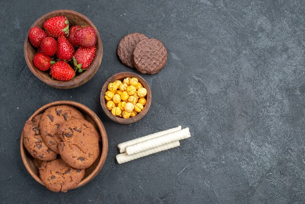 Vue de dessus fraises rouges fraîches avec des biscuits sucrés sur le gâteau aux biscuits au sucre de table noir