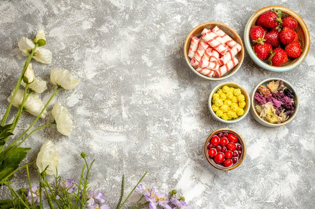 Vue de dessus fraises rouges fraîches avec des bonbons sur la surface blanche des fruits de bonbons de baies