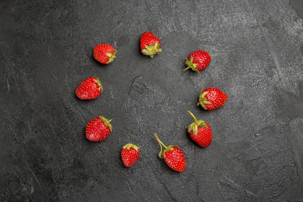 Vue de dessus fraises rouges fraîches bordées de couleur sombre table baies de fruits mûrs