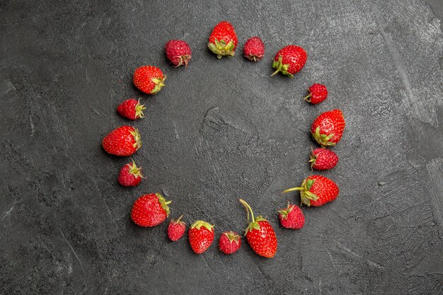 Vue de dessus fraises rouges fraîches bordées de fruits berry couleur tableau gris foncé