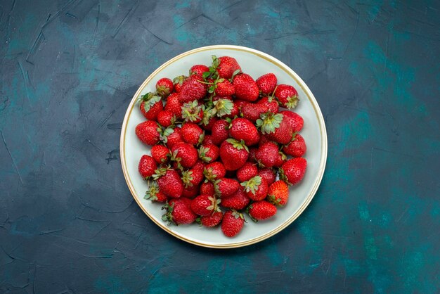 Vue de dessus fraises rouges fraîches fruits moelleux baies à l'intérieur de la plaque sur le fond bleu foncé berry fruit été doux