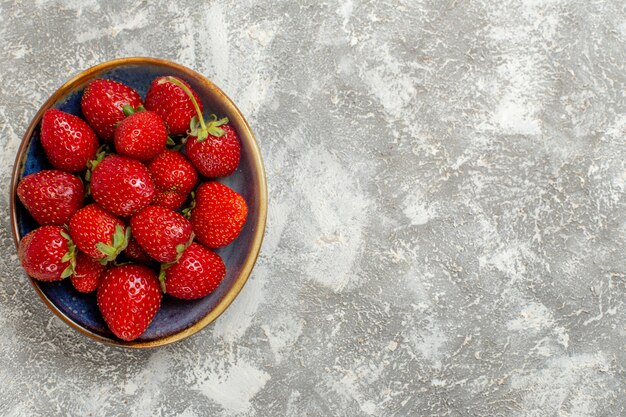 Vue de dessus fraises rouges fraîches à l'intérieur de la plaque sur fond blanc