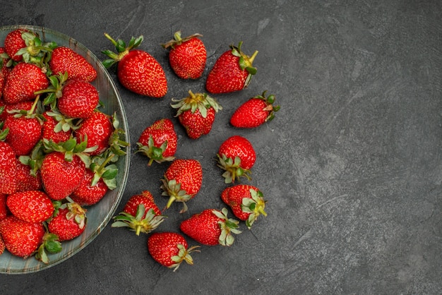 Vue de dessus fraises rouges fraîches à l'intérieur de la plaque sur fond gris