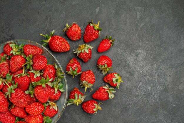 Vue de dessus fraises rouges fraîches à l'intérieur de la plaque sur fond gris