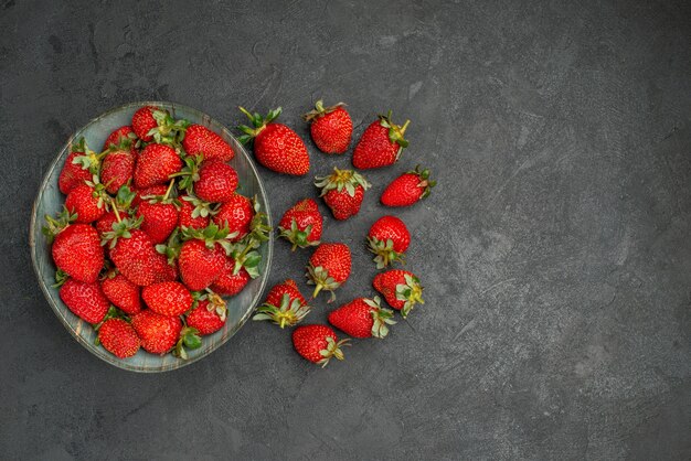 Vue de dessus fraises rouges fraîches à l'intérieur de la plaque sur fond gris