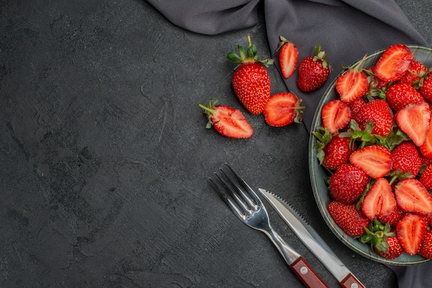 Vue de dessus des fraises rouges fraîches à l'intérieur de la plaque sur fond sombre