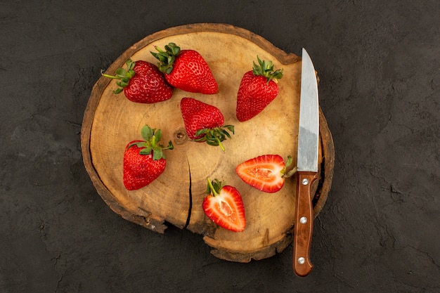 Vue de dessus des fraises rouges fraîches tranchées mûres sur le bureau brun foncé et