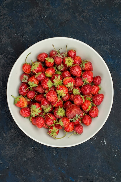 Une vue de dessus fraises rouges moelleuses et fraîches à l'intérieur de la plaque sur la couleur de fond sombre vitamine