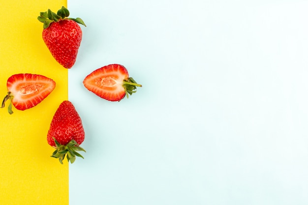 Vue de dessus des fraises rouges moelleuses juteuses sur le fond jaune bleu