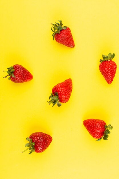 Vue de dessus des fraises rouges moelleuses juteuses isolé sur fond jaune