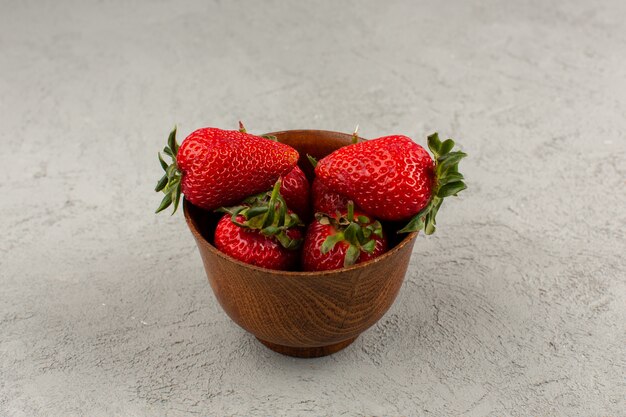 Vue de dessus des fraises rouges moelleux frais juteux à l'intérieur du pot brun sur le fond gris