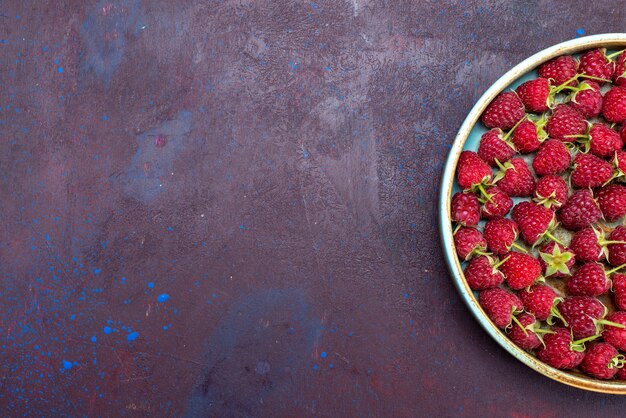 Vue de dessus framboises rouges fraîches baies mûres et aigres sur fond bleu foncé berry fruit doux été alimentaire vitamine