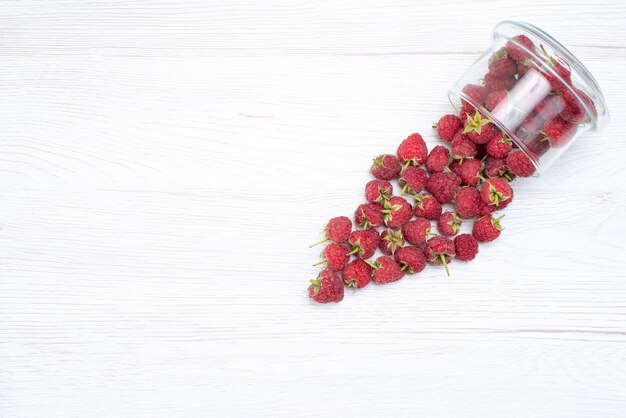 Vue de dessus des framboises rouges fraîches à l'intérieur et à l'extérieur de la plaque sur blanc clair, petits fruits frais