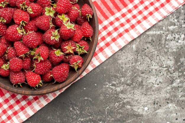 Vue de dessus des framboises rouges fraîches à l'intérieur de la plaque sur fond gris