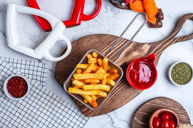 Vue de dessus des frites dans un panier avec du ketchup sur la planche