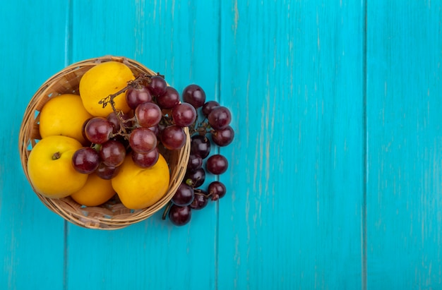 Photo gratuite vue de dessus des fruits comme nectacots et raisin dans le panier et sur fond bleu avec espace copie