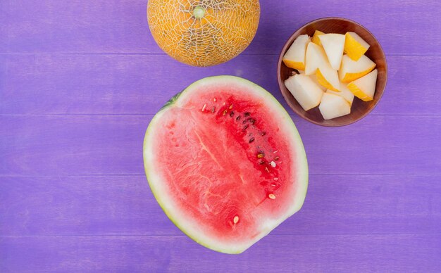 Vue de dessus des fruits comme pastèque coupée avec melon entier et tranché sur fond violet avec espace copie