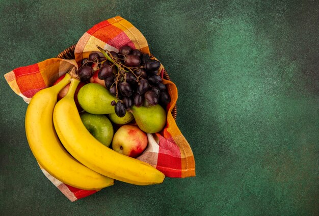 Vue de dessus des fruits comme poire pomme poire banane raisin dans le panier sur fond vert avec copie espace