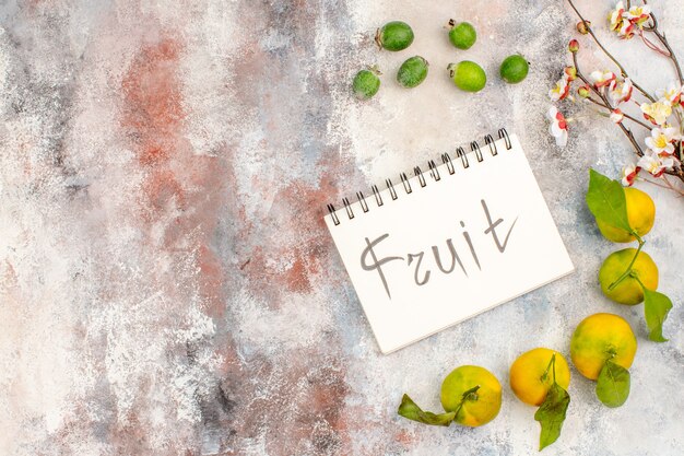 Vue de dessus des fruits frais de mandarines feykhoas écrits sur un ordinateur portable sur fond nu