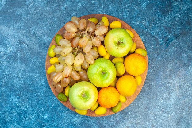 Vue de dessus fruits frais pommes mandarines et raisins sur table bleue