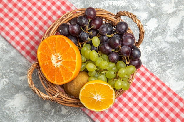 Vue de dessus des fruits frais raisins et oranges à l'intérieur du panier sur une surface blanche fruit mûr mûr vitamine frais