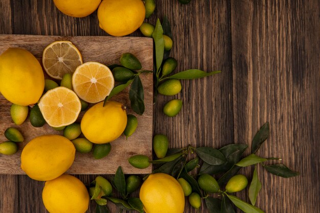 Vue de dessus de fruits frais tels que les kinkans et les citrons isolés sur une planche de cuisine en bois sur un mur en bois avec espace copie