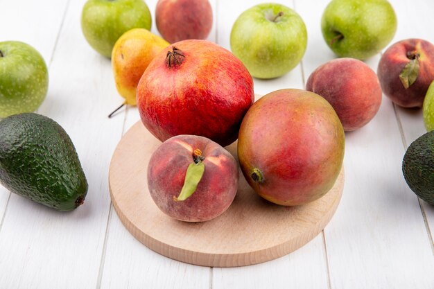 Vue de dessus de fruits frais tels que la mangue pêche grenade sur planche de cuisine en bois avec pommes poires pêches isolé sur blanc