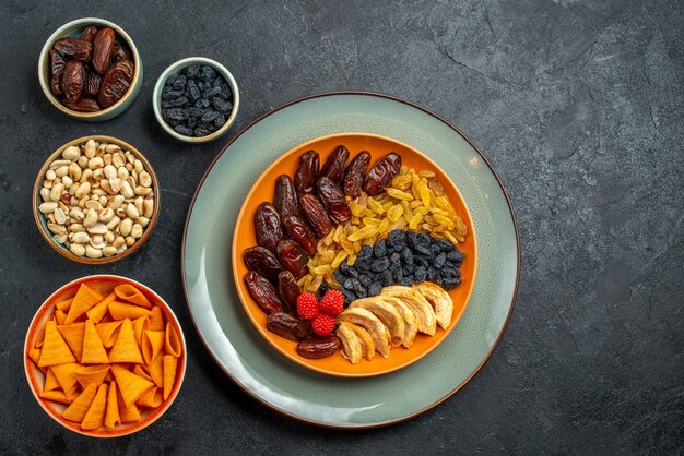 Vue de dessus des fruits secs avec différents raisins secs sur un espace gris foncé