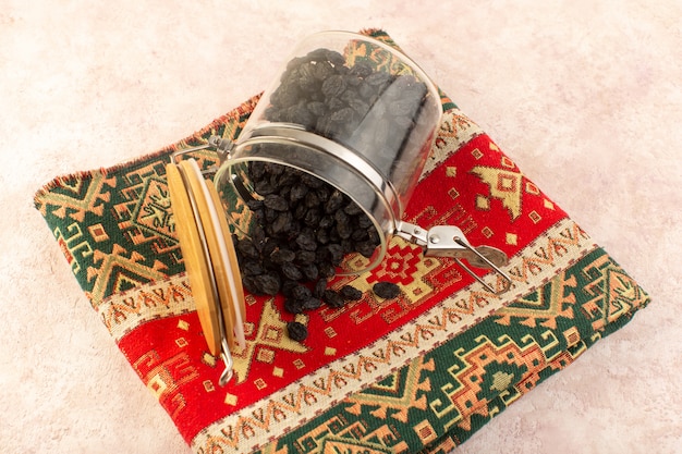 Photo gratuite une vue de dessus des fruits secs noirs à l'intérieur de la boîte ronde sur tapis conçu coloré sur rose
