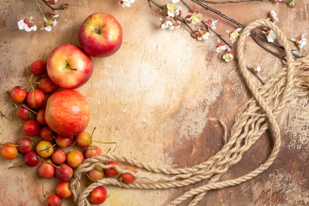 Vue de dessus des fruits les trois pommes appétissantes et des branches d'arbres de corde de cerisier