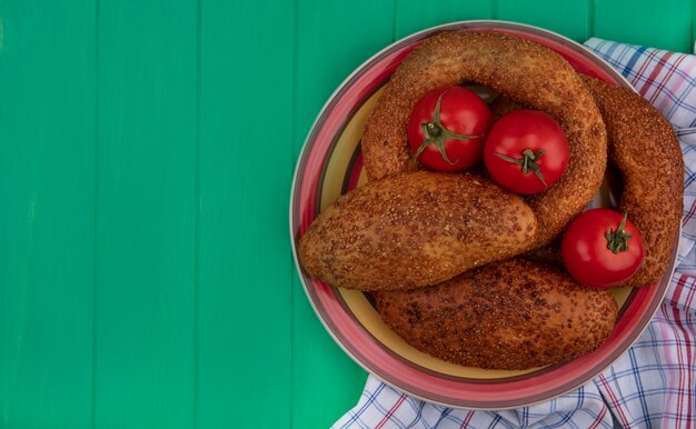 Vue de dessus des galettes molles et sésame sur un bol avec des tomates fraîches sur un chiffon sur un fond en bois vert avec copie espace