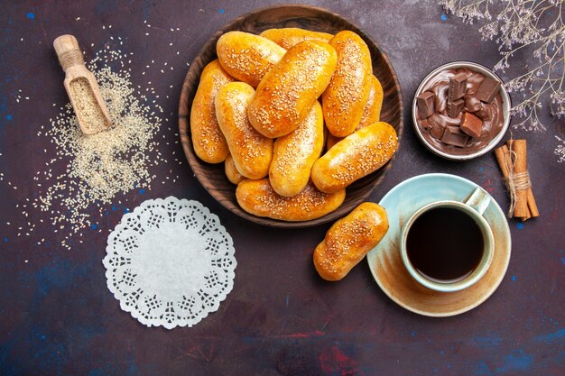 Vue de dessus des galettes sucrées avec une tasse de thé et de chocolat sur le bureau sombre repas pâtisserie pâte thé nourriture galette