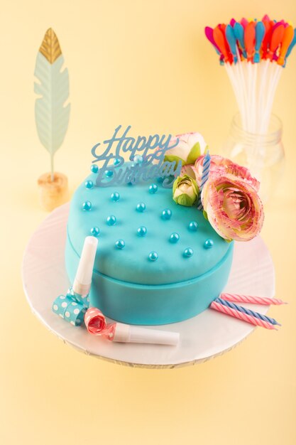 Une vue de dessus gâteau d'anniversaire bleu avec fleur sur le dessus sur le gâteau d'anniversaire de fête de célébration de bureau jaune