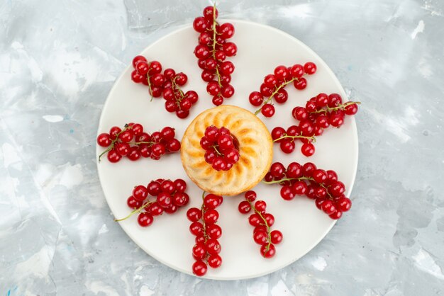 Une vue de dessus gâteau aux canneberges fruits rouges moelleux et juteux à l'intérieur de la plaque blanche sur le bureau léger gâteau aux fruits de baies